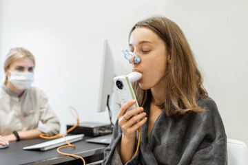 Young woman with doctor during a spirography test, measuring breathing movements with spirometer at medical Spa salon