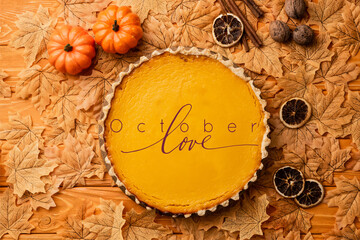 Wall Mural - top view of pumpkin pie with autumnal decoration near october love lettering on wooden background