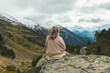 © Wirestock Exclusives - Rear view of a Latina woman sitting on a rock covered in moss Zillertal Valley, Austria