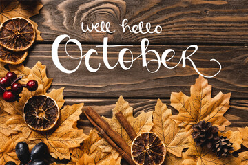 Wall Mural - Top view of autumnal decoration and foliage near well hello October lettering on wooden background