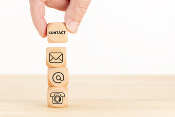 Poster - Contact us concept. Hand holding a wooden block with text and a pile of dices with communication icon