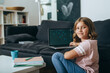 © cherryandbees - young girl sitting on the floor at her home and using computer for online education