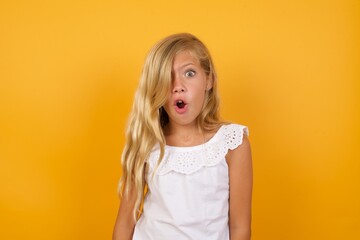 beautiful caucasian young girl standing against yellow background expressing disgust, unwillingness,