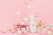 White Angel With Christmas Ornaments Over Pink Background. Minimal Picture For Winter Holidays