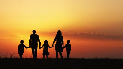 Wall Mural - Silhouettes of happy family holding the hands in the meadow during sunset. Happy family enjoying life together. Happy young family spending time together outside in green nature. Back view.