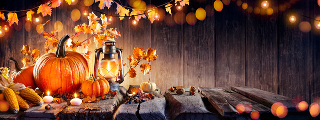 Wall Mural - thanksgiving - old table with pumpkins and corns with bokeh lights in dark background