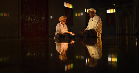 Wall Mural - muslim boy sitting in mosque with islamic teacher learning koran book