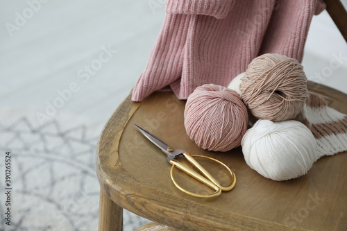 Fotomural Yarn balls and scissors on wooden chair indoors, space for text