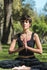 Canvas Print - Vertical shot of a young Caucasian female doing yoga practice in the park