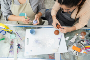 Wall Mural - Top view of the hands of women pastry chefs working with fondant to decorate a cake - hands molding clay with tools and coloring - women artisans