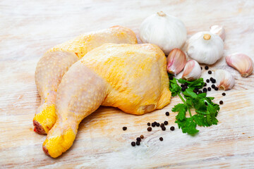 Home cooking. Fresh raw chicken legs and condiments prepared for roasting on wooden table