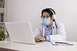 © steafpong - Young Asian Doctor Man in Lab Coat or Gown with Stethoscope Wear Face Mask and Glasses and Headphone Video Call or Video Conference with Patient Via Laptop Computer in Office