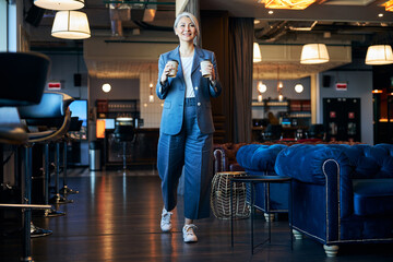 Wall Mural - Charming woman with two cups of coffee walking in cafe