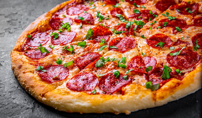 Pepperoni Pizza with Mozzarella cheese, salami, Tomato sauce, pepper, Spices. Italian pizza on Dark grey black slate background