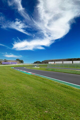 Wall Mural - Hairpin bend and turn exit with curb and green field on motor sport circuit asphalt track