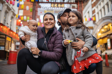 Two happy parents and their two daughters posing in a blurry Chinatown alley