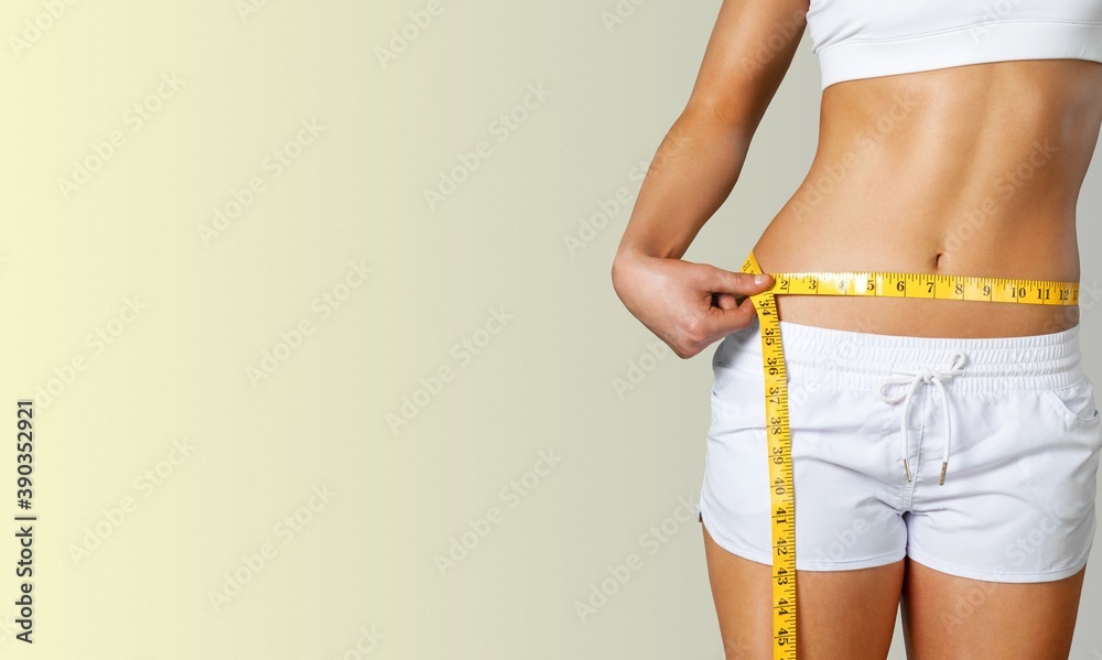 Slim young woman measuring her thin waist with a tape measure - obrazy, fototapety, plakaty 