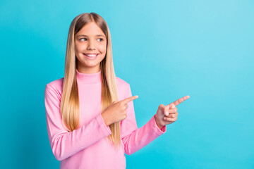 Poster - Photo portrait of curious girl pointing with finger showing looking at copyspace isolated on vibrant teal color background