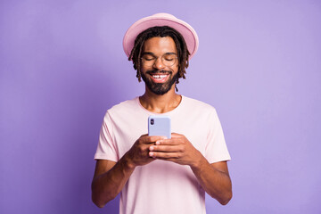 Wall Mural - Photo portrait of man holding phone in two hands typing isolated on vivid purple colored background