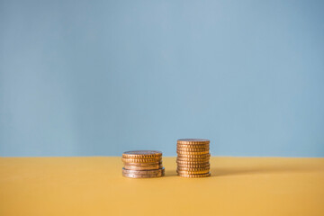 Two stacks of coins on a blue background. Financial concept.