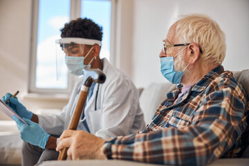 Wall Mural - Aged man in a mask looking at a doctor