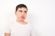 © Jihan - Caucasian young boy standing against white background , looks pensively aside, plans actions after university, imagines what to do Thinks over about new project.