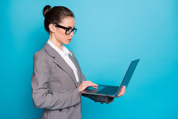 Poster - Profile side view of attractive focused busy lady holding in hand using laptop isolated over bright blue color background