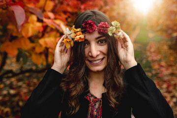 Close up young woman portrait in a field wearing a flower crown Autumn colors looking at the camera. Fall season concept.