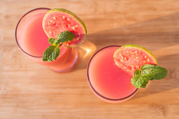 Directly above shot of glass of organic Guava juice with fresh guava on wooden table