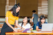 © shine - Group of young asian students studying together. Young people sitting at the table and studying on laptop computer and reading book.