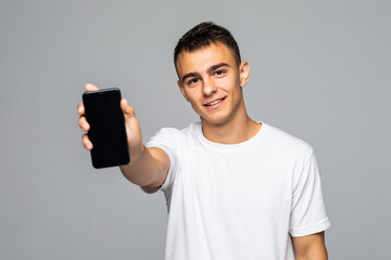 Wall Mural - Portrait of a smiling man showing blank smartphone screen on a white background