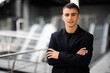 © dianagrytsku - Portrait of an elegant young businessman standing with arms crossed in office