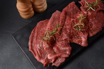 Raw beef steaks with spices and rosemary.