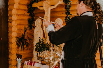 rite of sacrament of epiphany child baby in church. A priest in a cassock lights two candles from one.