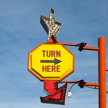 Turn Here, Yellow Traffic Sign With Arrow, On A Gantry With A Silver Star Shape