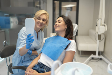 Female dentist in dental clinic providing examination and treatment of oral cavity for female patient.