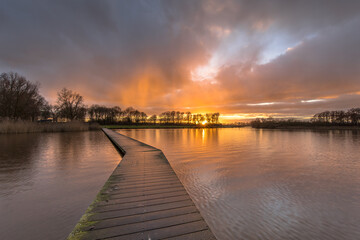 Poster - Wooden walkway in lake under orange sunset