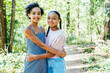 © Inti St. Clair - Portrait of smiling teen sisters hugging outside in nature park
