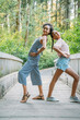 © Inti St. Clair - Teen girls striking funny pose on bridge in nature park