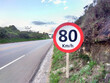 © Marlon - 80 kilometers per hour speed limit sign, highway alongside and blue sky with clouds in the background