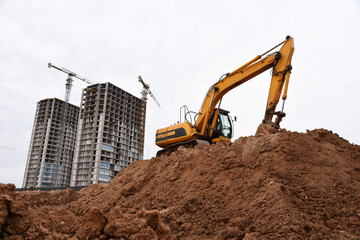 Excavator during earthmoving at construction site. Backhoe dig ground for the construction of foundation and laying sewer pipes district heating. Earth-moving heavy equipment on road works