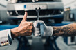 Close up shot of car mechanic worker's and business man costumer's hands showing thumb up sign during periodic car condition check.