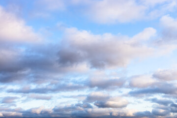 Poster - low fluffy gray and white clouds in blue sky in autumn twilight