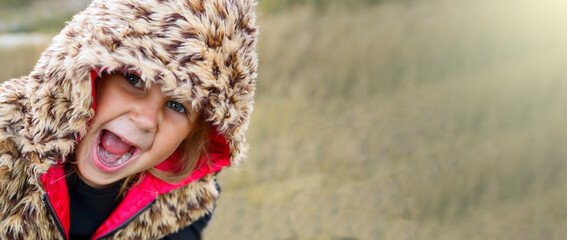 Child portrait, close-up. Girl outdoors in nature. Beautiful girl 3 years old. Autumn photo. Children's emotions. The girl in the hood. Copy space