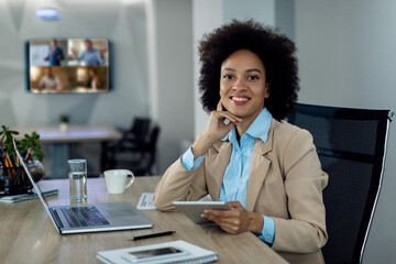 Wall Mural - Happy black businesswoman working on digital tablet in the office.