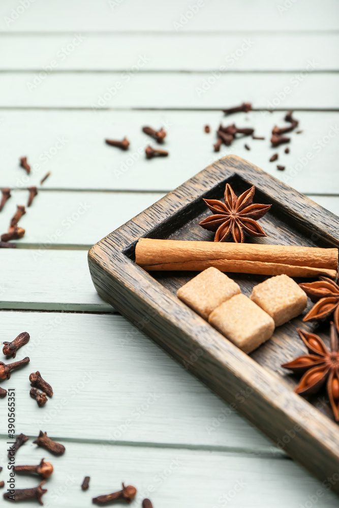 Plate with cinnamon, anise and sugar on wooden background