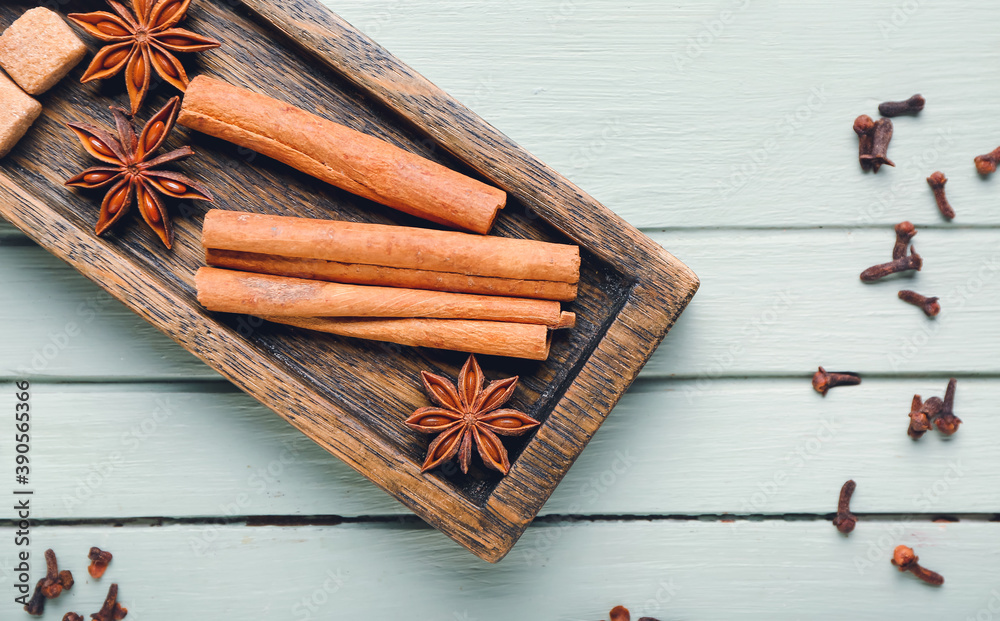 Plate with cinnamon, anise and sugar on wooden background