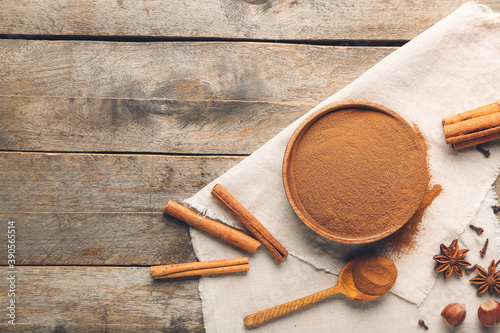 Fotomural Bowl and spoon with cinnamon powder on wooden background
