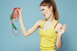 Fototapeta  - Woman with skipping rope sport exercise yellow tank top blue background