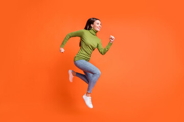 Poster - Full body profile side photo of young attractive crazy girl happy smile run jump up look empty space isolated over orange color background